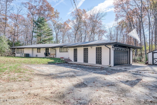 view of front of property featuring cooling unit, a shed, and a garage