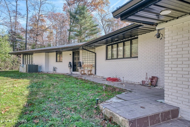 doorway to property featuring a lawn and central air condition unit