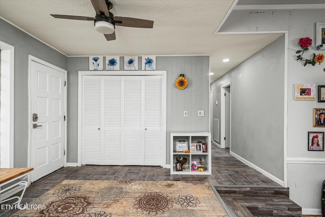 foyer entrance featuring dark parquet flooring, wooden walls, ceiling fan, ornamental molding, and a textured ceiling