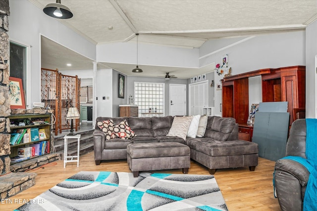 living room with ceiling fan, a textured ceiling, and light hardwood / wood-style flooring