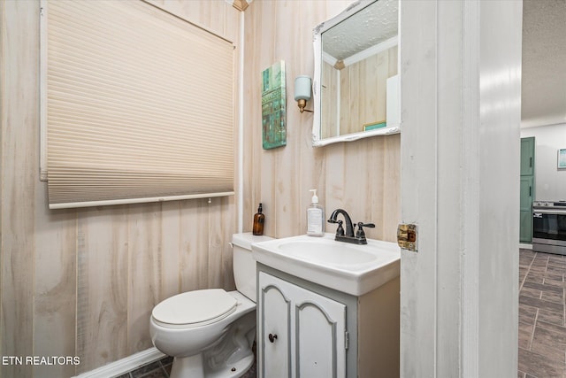 bathroom with vanity, toilet, and wooden walls