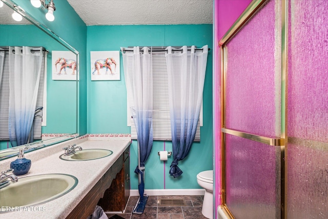 bathroom with tile patterned flooring, a textured ceiling, toilet, a shower with door, and vanity