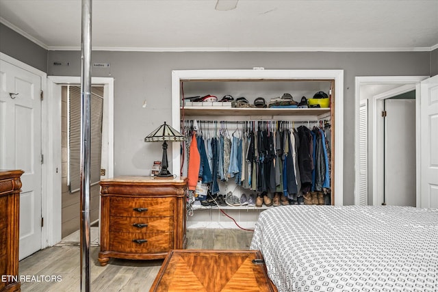 bedroom featuring wood-type flooring, a closet, and ornamental molding