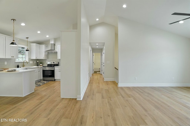 kitchen featuring white cabinets, stainless steel electric range oven, hanging light fixtures, and wall chimney range hood