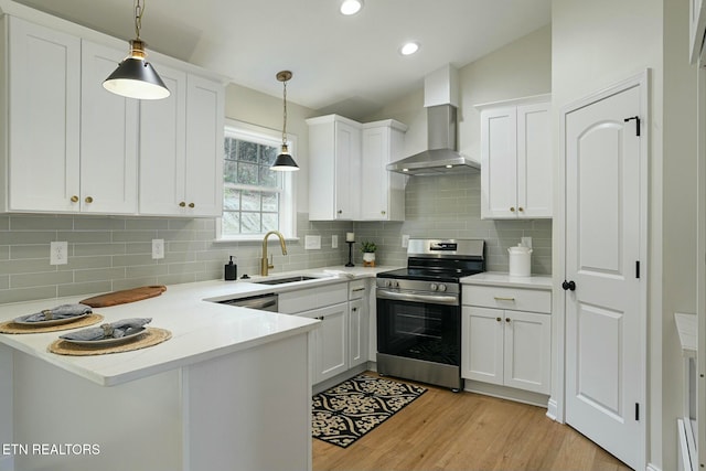 kitchen with wall chimney exhaust hood, sink, decorative light fixtures, stainless steel appliances, and white cabinets