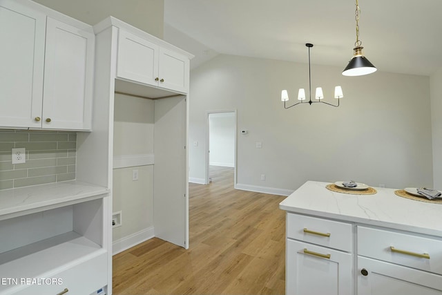 kitchen with white cabinetry, backsplash, lofted ceiling, and hanging light fixtures