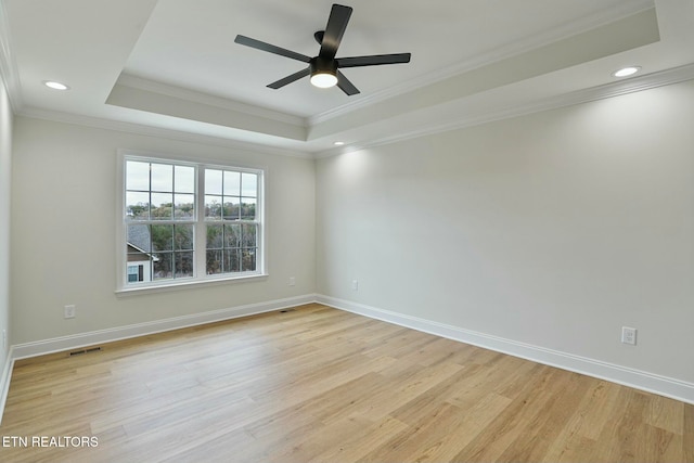 spare room with a raised ceiling, ornamental molding, ceiling fan, and light wood-type flooring