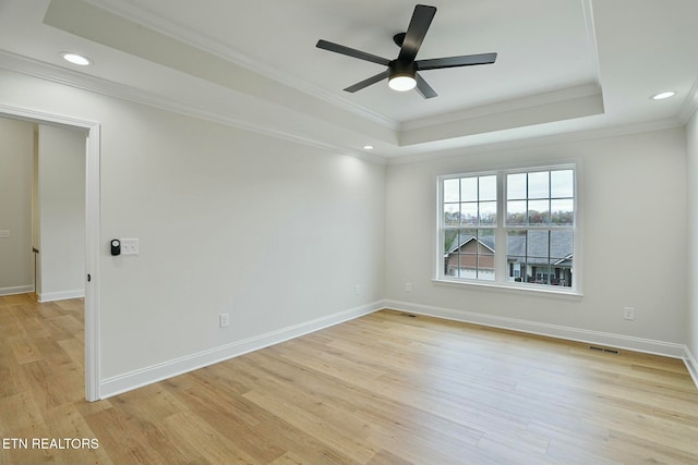 empty room featuring ornamental molding, a raised ceiling, and light hardwood / wood-style floors