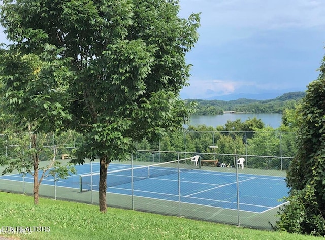 view of sport court featuring a water view, fence, and a view of trees