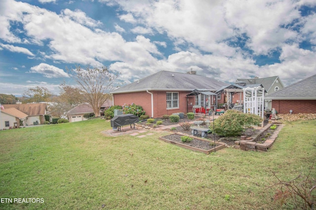 back of house with a vegetable garden, a lawn, a patio area, a pergola, and brick siding