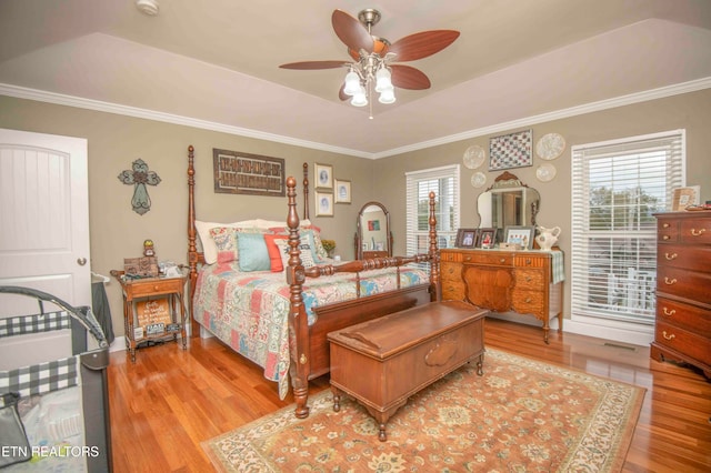 bedroom featuring light wood-type flooring, a tray ceiling, ceiling fan, and crown molding