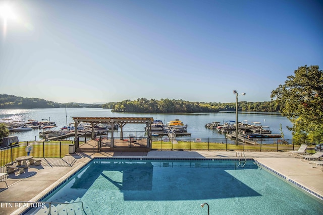 community pool featuring a water view, fence, and a patio