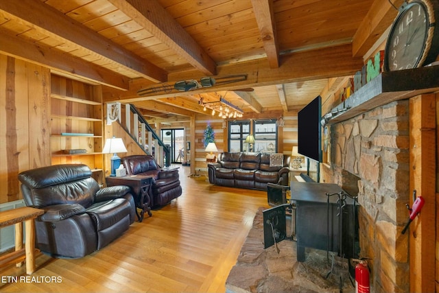 living room with wood walls, a stone fireplace, light wood-type flooring, beamed ceiling, and wood ceiling