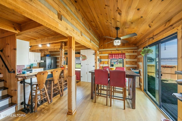 dining space featuring wood ceiling, ceiling fan, wooden walls, a water view, and light hardwood / wood-style floors