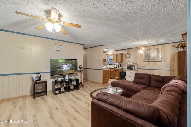 living room with ceiling fan, light wood-type flooring, and a textured ceiling