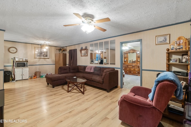 living room featuring light wood-type flooring, a textured ceiling, and ornamental molding