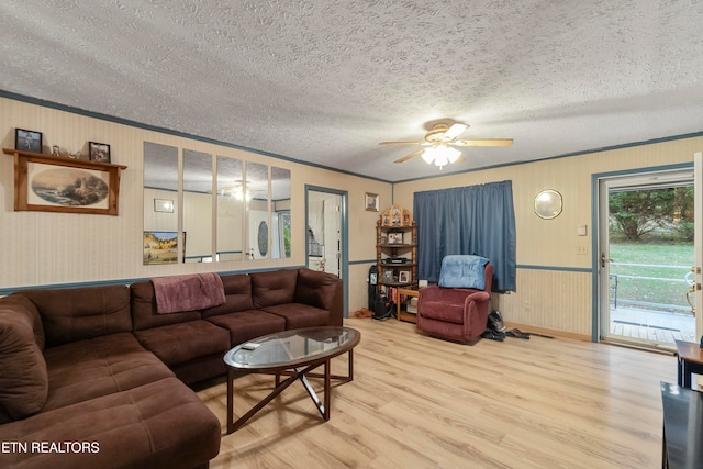 living room with hardwood / wood-style flooring, ceiling fan, ornamental molding, and a textured ceiling