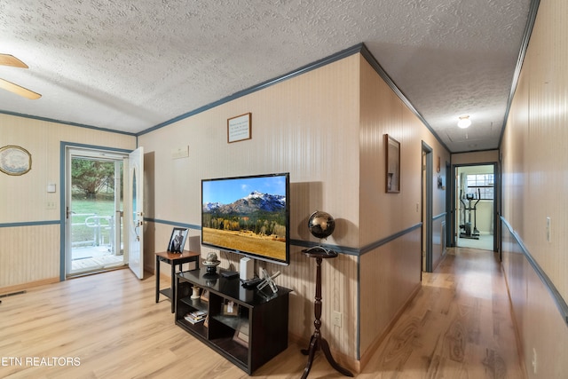 living room with light hardwood / wood-style floors, ornamental molding, and a textured ceiling