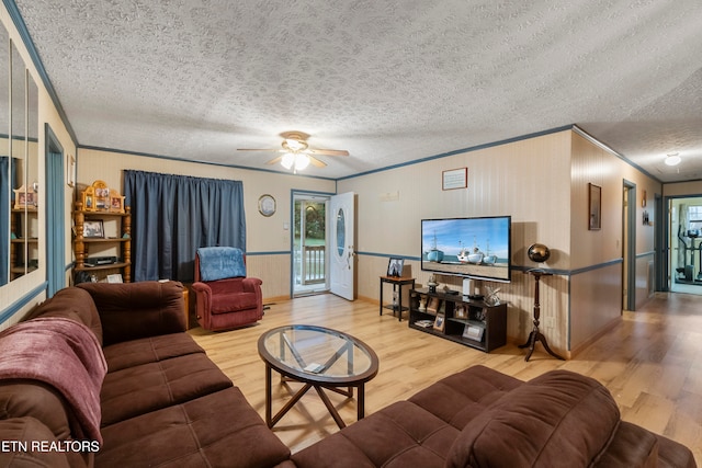 living room with ceiling fan, wood-type flooring, a textured ceiling, and ornamental molding