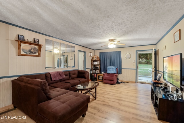 living room with ceiling fan, light hardwood / wood-style floors, a textured ceiling, and ornamental molding