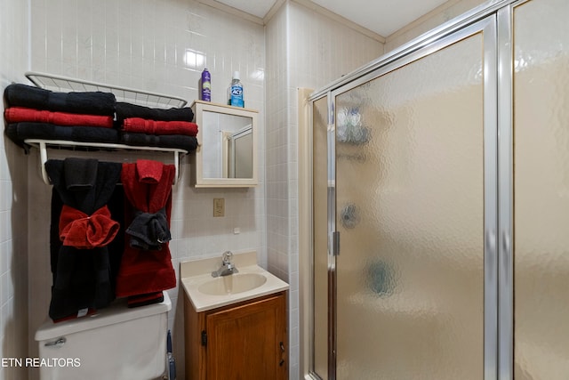 bathroom featuring vanity, toilet, a shower with door, and tile walls