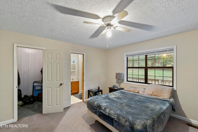 bedroom with ensuite bath, ceiling fan, light colored carpet, and a textured ceiling