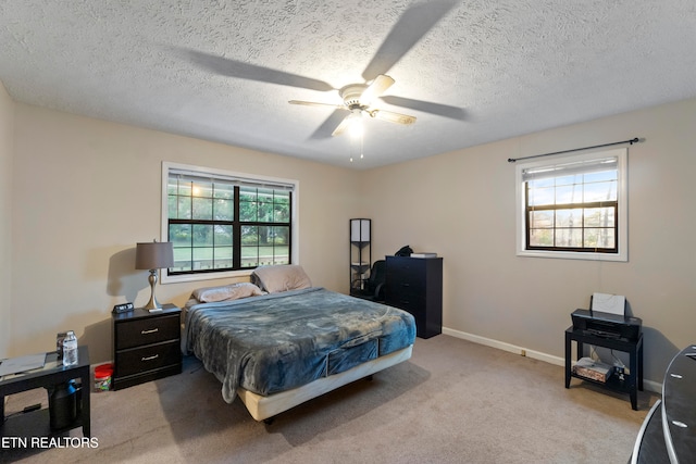 bedroom with ceiling fan, light carpet, and a textured ceiling