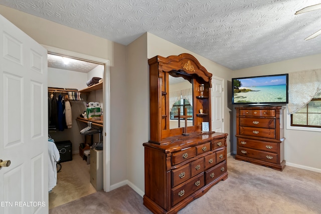 bedroom featuring a textured ceiling, a spacious closet, light carpet, and a closet