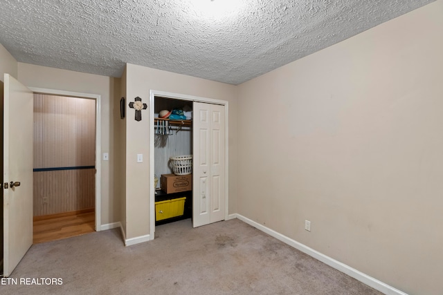 unfurnished bedroom with light colored carpet, a textured ceiling, and a closet