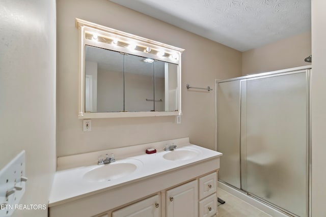 bathroom with vanity, a shower with shower door, and a textured ceiling