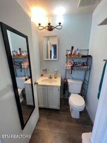 bathroom with vanity, a textured ceiling, hardwood / wood-style flooring, and toilet