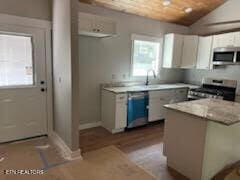 kitchen with white cabinets, light wood-type flooring, appliances with stainless steel finishes, and vaulted ceiling