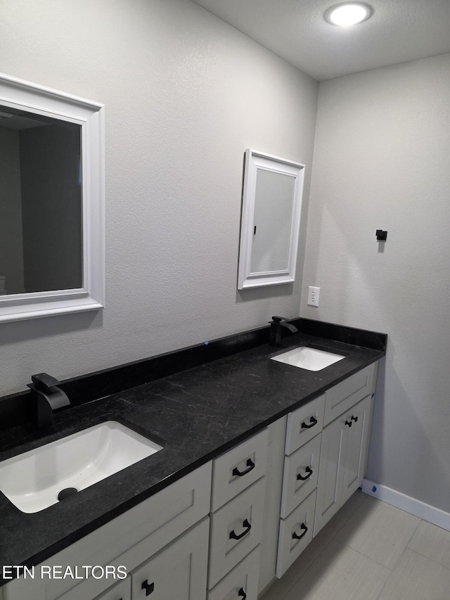 full bath featuring a sink, baseboards, and double vanity