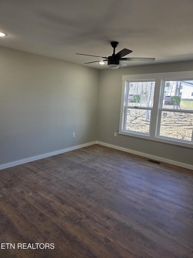 unfurnished room featuring dark wood-style flooring, visible vents, and baseboards