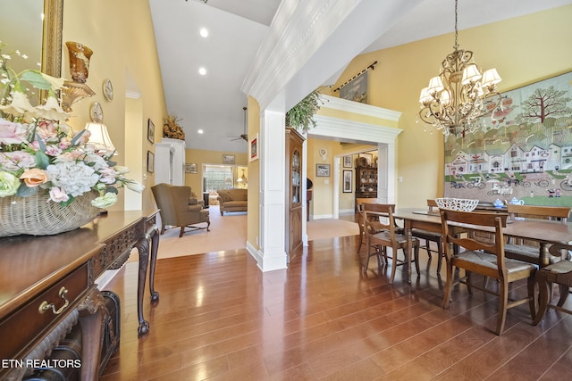 dining room with hardwood / wood-style flooring, ceiling fan with notable chandelier, and a towering ceiling