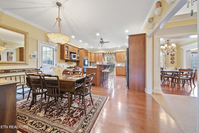 dining room featuring ceiling fan with notable chandelier, light hardwood / wood-style floors, and ornamental molding