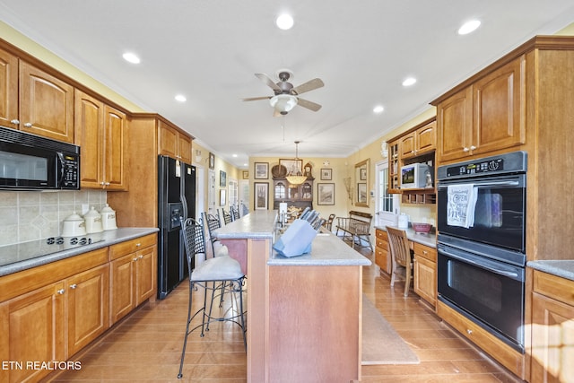 kitchen featuring a kitchen breakfast bar, a center island, light hardwood / wood-style floors, and black appliances