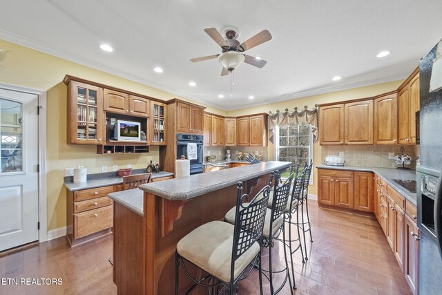 kitchen featuring a kitchen breakfast bar, a center island, backsplash, and black appliances