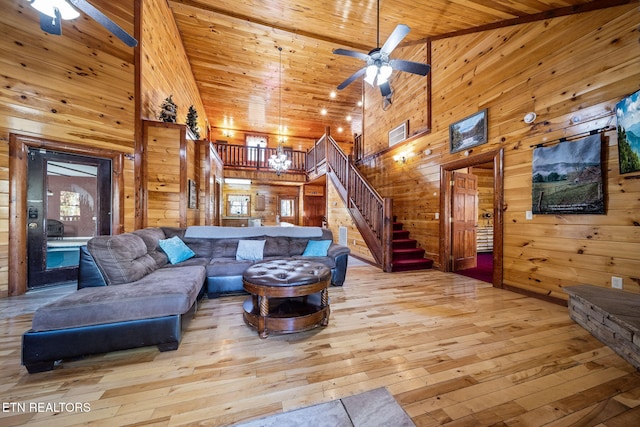 living room featuring a high ceiling, light wood-type flooring, wood ceiling, and wood walls