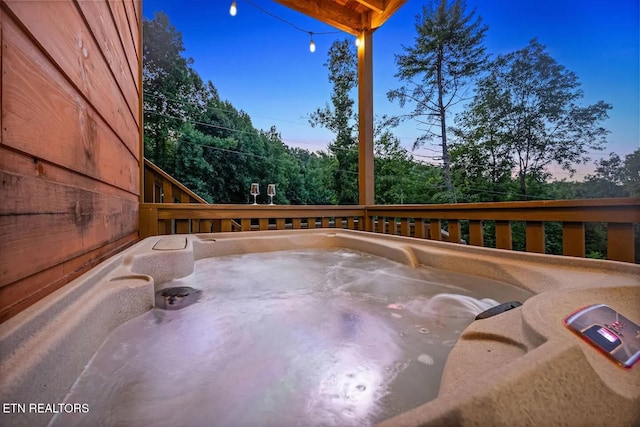 deck at dusk featuring a hot tub