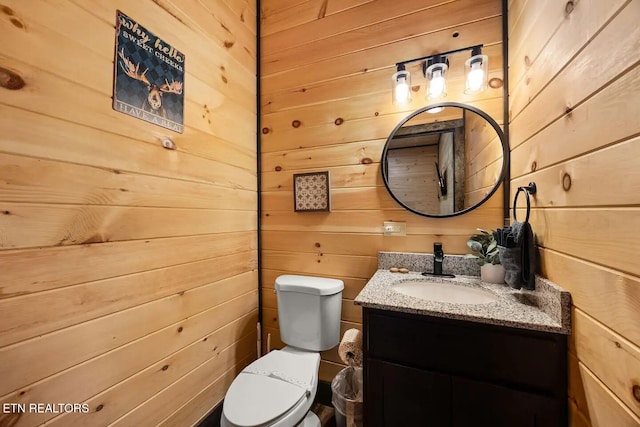 bathroom with wooden walls, vanity, and toilet