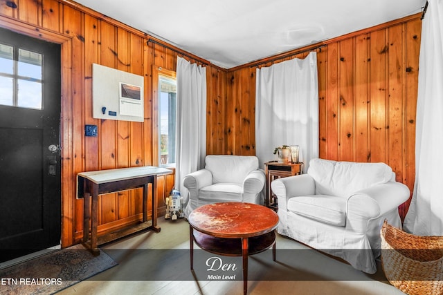 sitting room with plenty of natural light, wood walls, and light hardwood / wood-style flooring