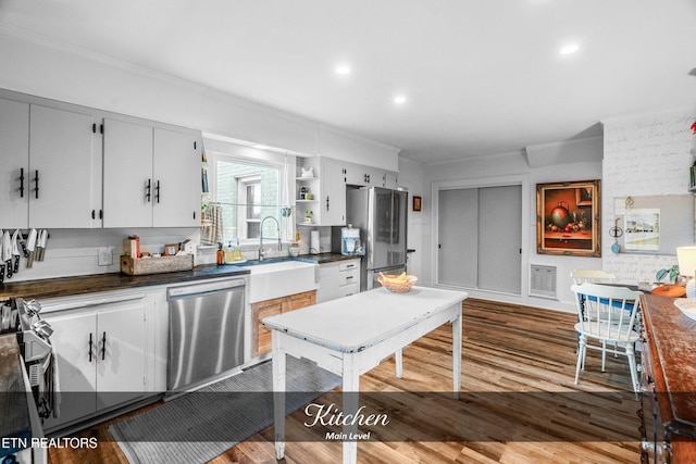 kitchen with white cabinets, wood-type flooring, sink, and appliances with stainless steel finishes