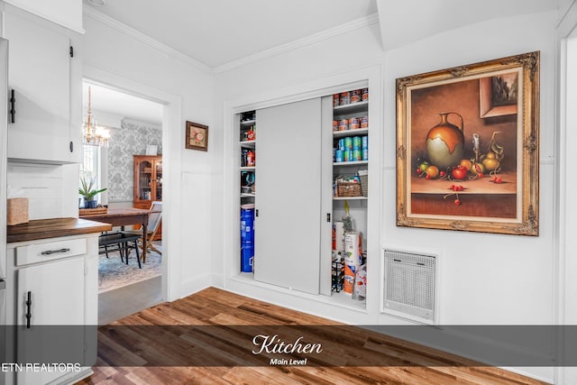 interior space with built in shelves, a chandelier, wood-type flooring, and ornamental molding