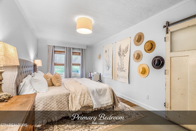 bedroom featuring a barn door, ornamental molding, and a textured ceiling