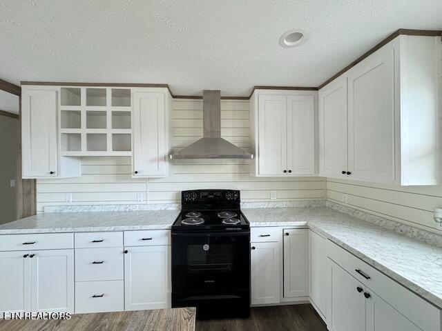 kitchen with a textured ceiling, black electric range, white cabinets, and wall chimney range hood