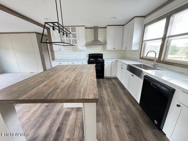 kitchen with black appliances, wood counters, white cabinetry, and wall chimney range hood