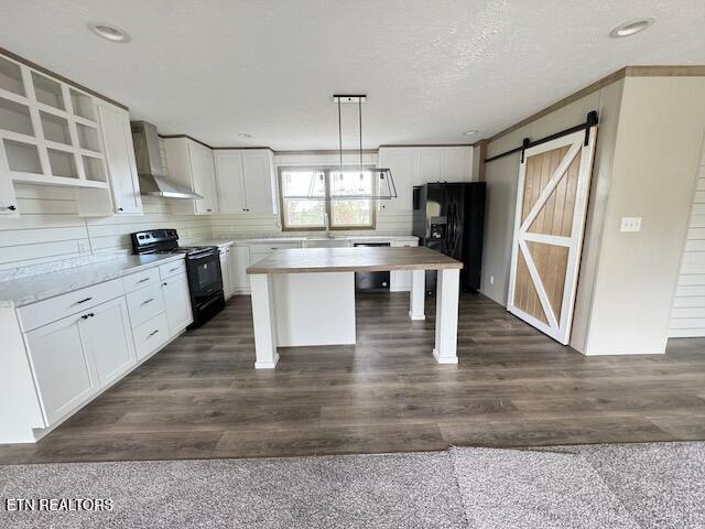 kitchen with black appliances, decorative light fixtures, dark hardwood / wood-style floors, and wall chimney range hood