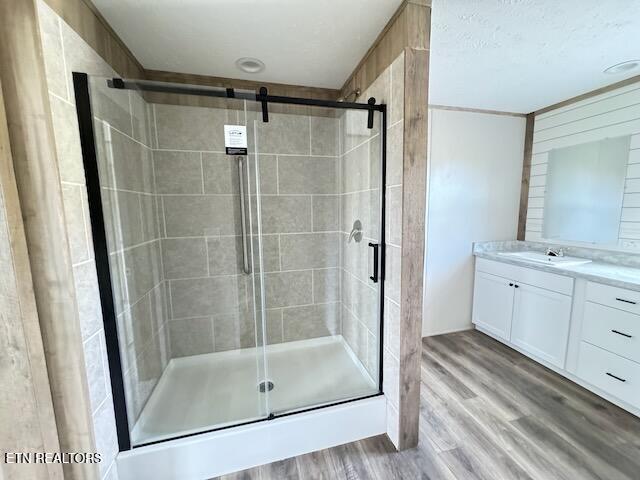 bathroom with hardwood / wood-style floors, vanity, and an enclosed shower