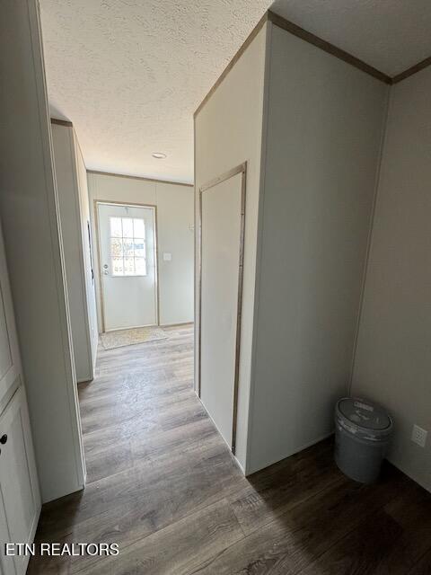 corridor featuring crown molding, hardwood / wood-style floors, and a textured ceiling